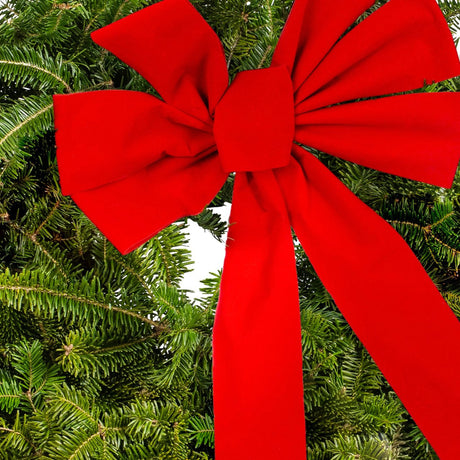 Large red bow on a green winter wreath made from Christmas tree clippings, zoomed so the focal point is the red Christmas bow