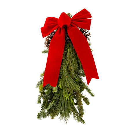 This assorted bunch of evergreens hangs down like Santa's beard, with a large red bow sitting up top with pinecones that make a unique Christmas decoration on a white backdrop