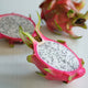 White Flesh Dragon Fruit with Pink skin that has green tips. This fruit is from the Hylocereus undatus cactus and is displayed on a white textured background.